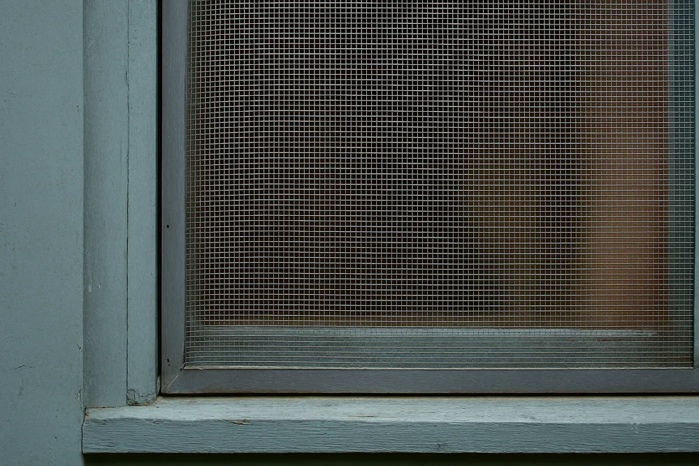 A fine metal mesh fixed over a painted timber window frame — bushfire screens and mesh, Blue Mountains. Illustrative example.